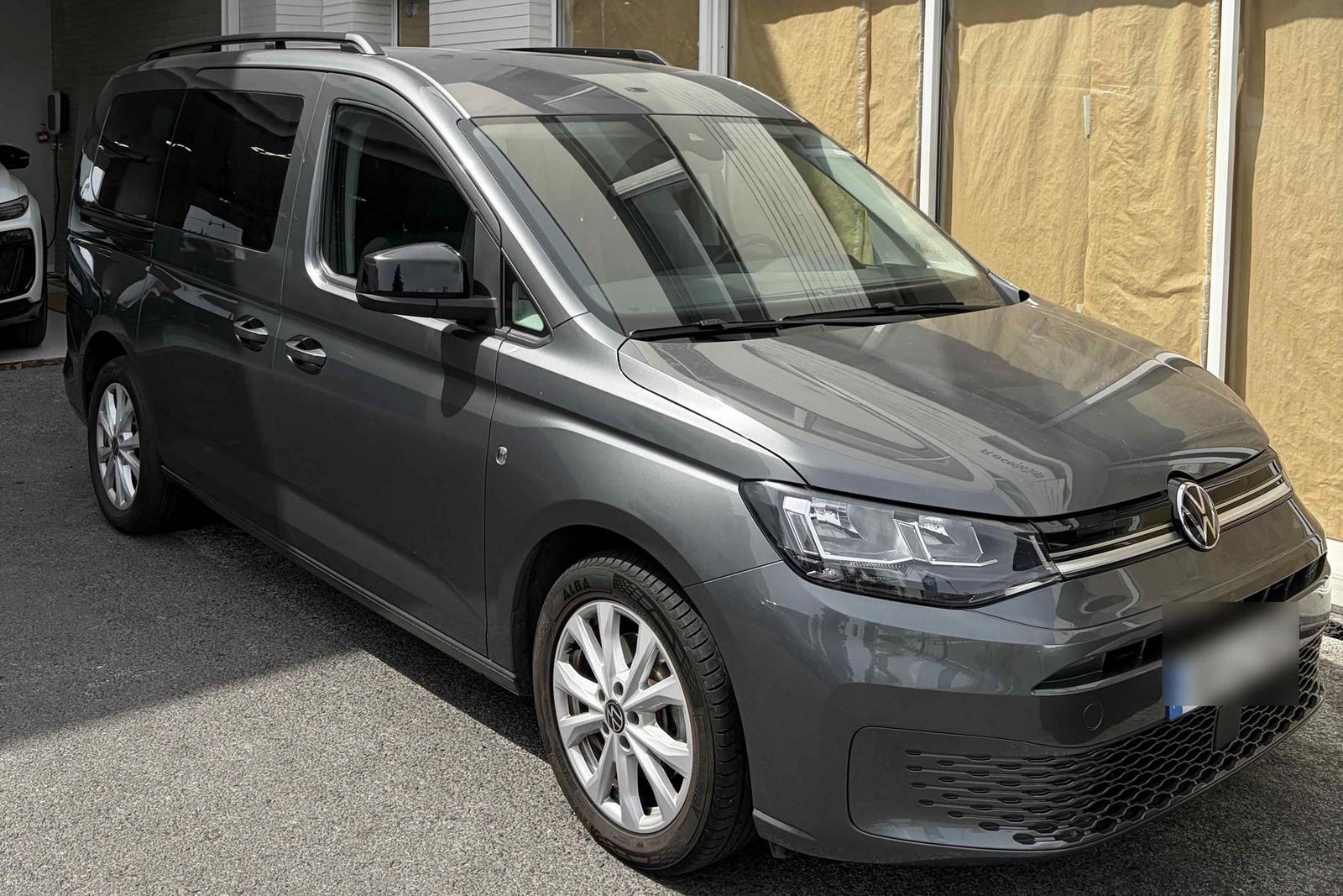 Our grey VW Caddy, seen from the front right, parked on the street