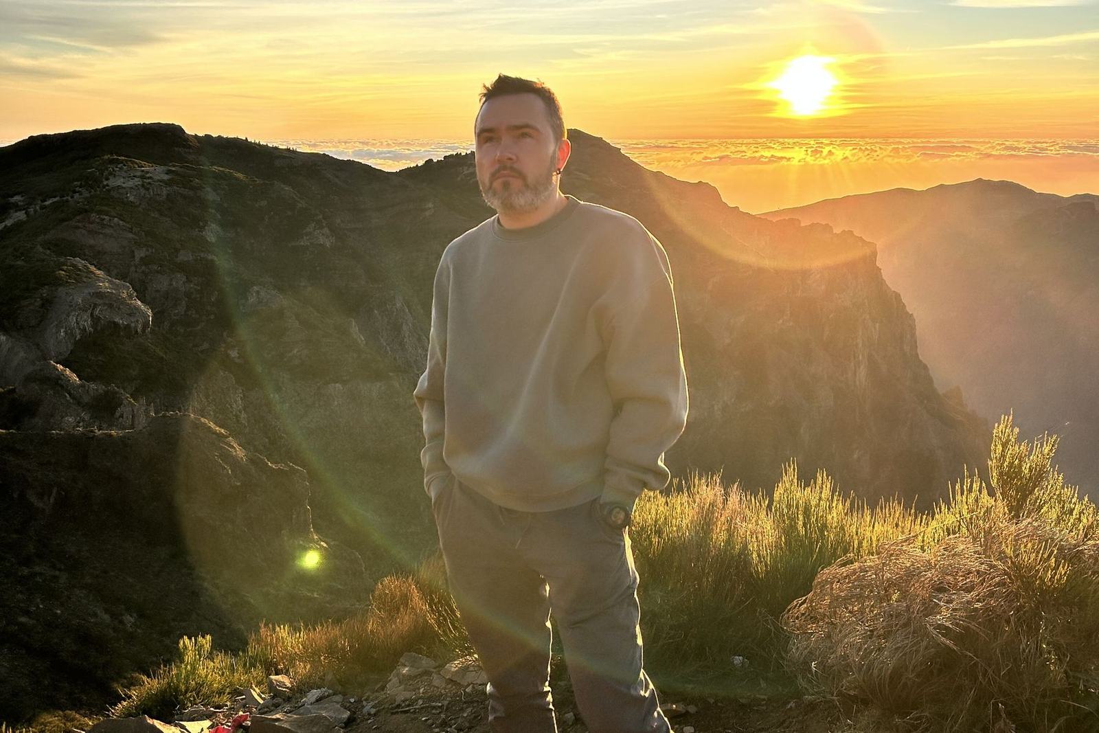 Your driver at the Pico do Arieiro viewpoint at sunrise, the sun low over a sea of cloud behind the ridges