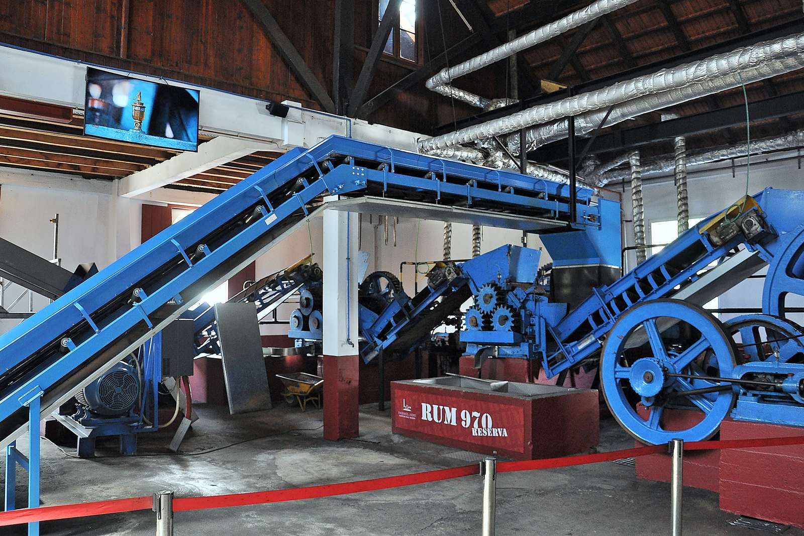 The blue cane-crushing mill and conveyors inside the Engenhos do Norte distillery in Porto da Cruz